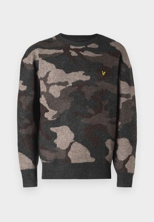 Kameramønstret genser i grått, brunt og beige. Laget av mykt strikket stoff med rund hals og ribbede mansjetter. Har en liten logo.