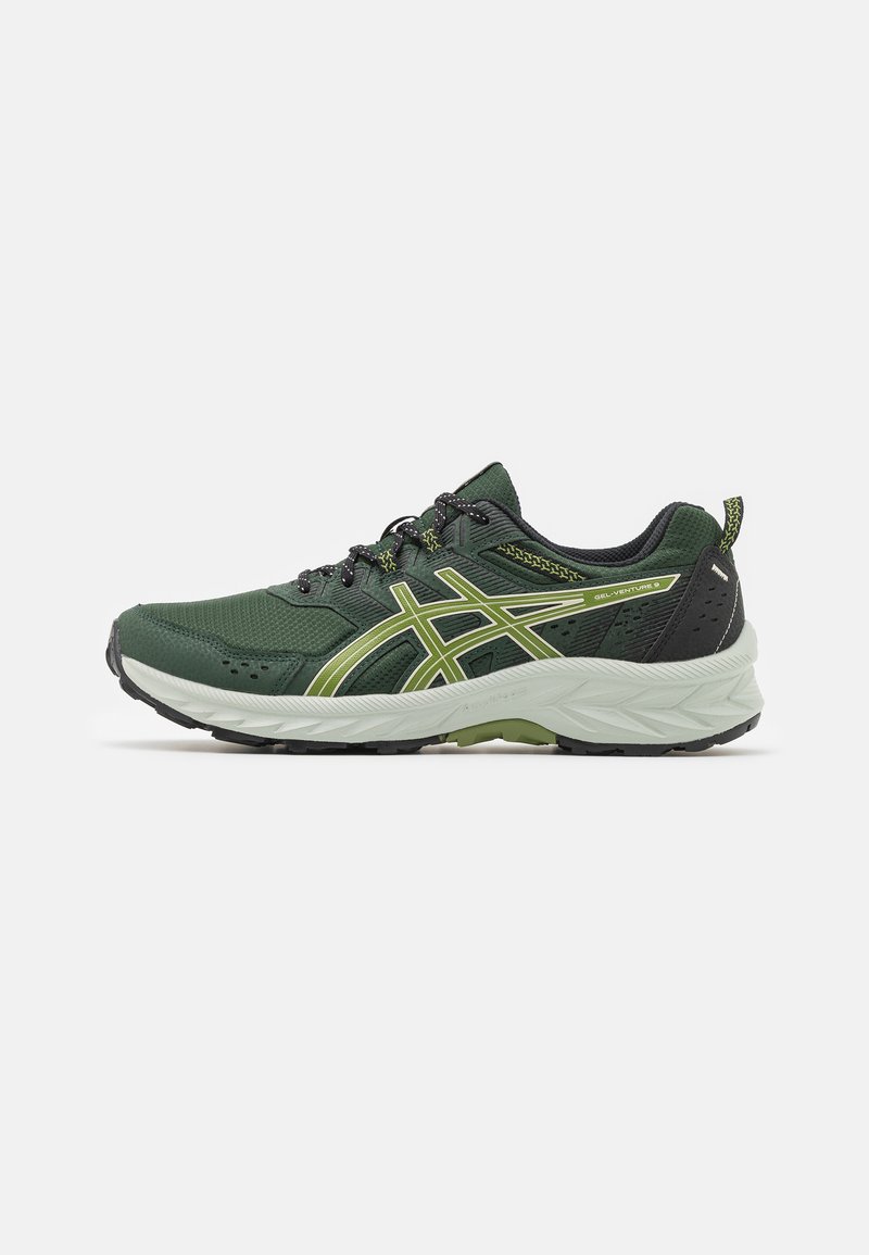 Zapatilla de correr en verde oscuro y negro con acentos en verde claro, parte superior de malla, suela blanca acolchada y franjas laterales con marca, vista de perfil.