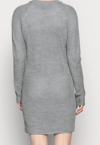 Robe tricotée grise à manches longues, avec des poignets côtelés et un motif texturé. La robe a une coupe décontractée et un col rond.