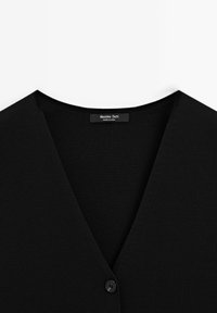 Schwarze Rippstrickjacke mit tiefem V-Ausschnitt und einem einzigen Knopfverschluss, gekennzeichnet mit "Massimo Dutti." Der Hintergrund ist weiß.