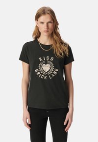 Camiseta de algodón negra con mangas cortas y escote redondo, que presenta un gráfico desgastado en blanco que dice "KISS BRICK LANE" rodeado de hojas de laurel.