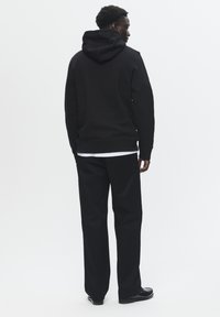 Black hoodie with a drawstring hood, paired with black pants. Smooth texture, fitted design, and minimalistic style with no visible branding.