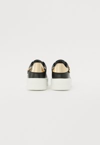 Black leather sneakers with gold accent on the heel, white sole, rounded shape, and textured detailing on the back strap.