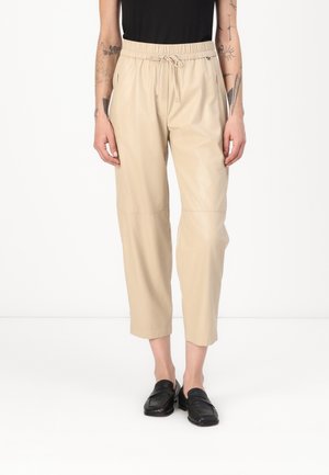 Beige, cropped, faux leather pants with an elastic waistband and drawstring, featuring side pockets and a smooth, glossy texture.