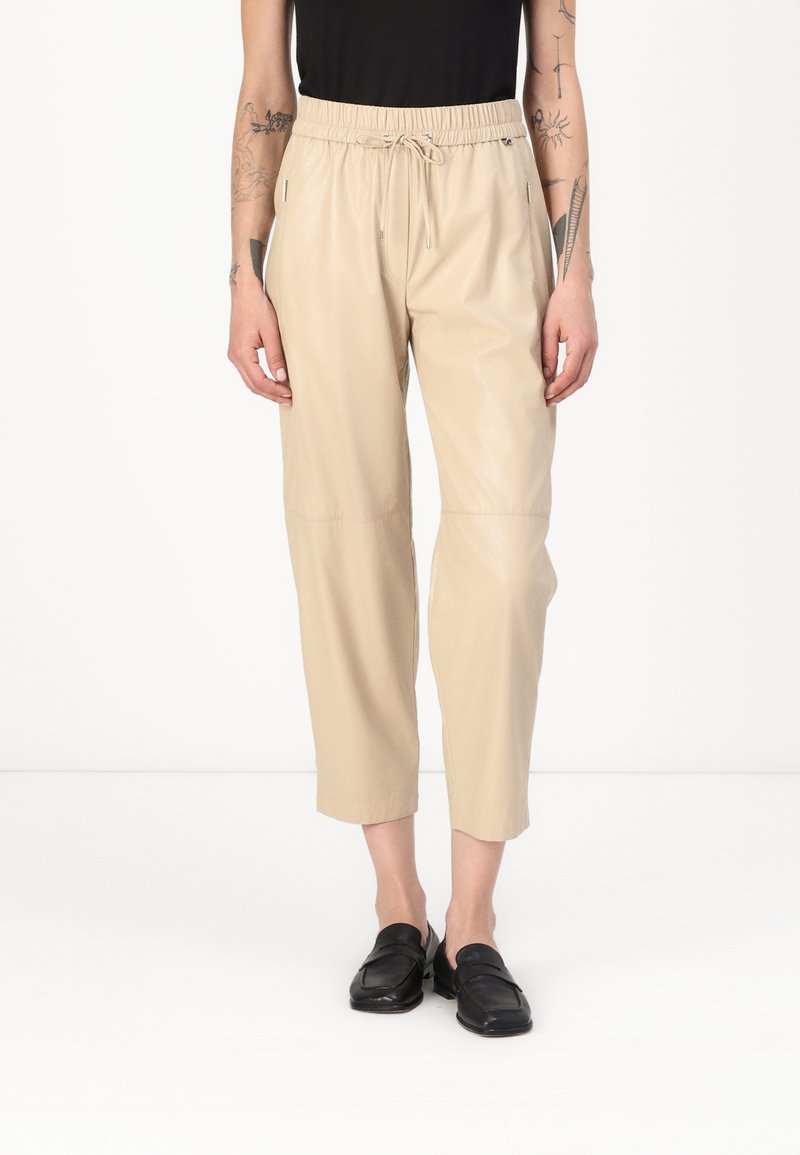Beige, cropped nep leren broek met een elastische tailleband en trekkoord, voorzien van zijzakken en een gladde, glanzende textuur.