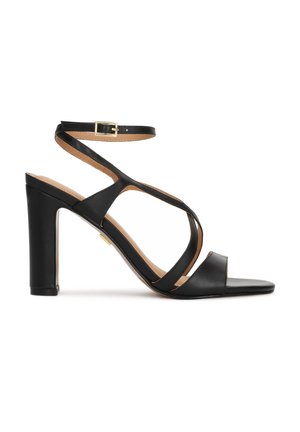 Juodos aukštakulnės basutės su kulkšnies dirželiu, kryžminiais dirželiais ant pėdos, atvira koja ir blokuota kulniuku ant balto fono.