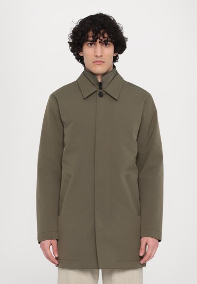 Cappotto verde oliva con colletto a punta, chiusura frontale con cerniera e bottoni. Presenta tasche laterali e una texture liscia e opaca.