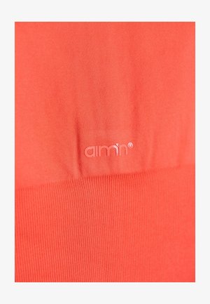 Tessuto color corallo con una texture liscia. Presenta un logo tonale "aimn®" impresso sopra una sezione a coste nella parte inferiore.