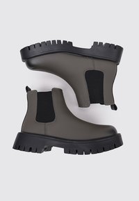 Botas Chelsea gruesas de goma en verde oliva oscuro con paneles elásticos negros en los costados y suelas gruesas negras con dibujo; diseño elegante y acabado mate.