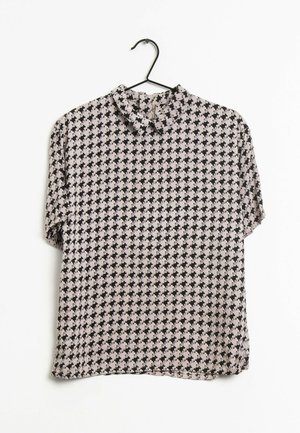 Bluzka z krótkim rękawem z czarno-beżowym wzorem w pepitkę, z krótkim, stojącym kołnierzykiem, zawieszona na czarnym wieszaku na białym tle.