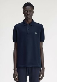 Polo shirt blu navy in cotone con pattina a tre bottoni e maniche corte. Presenta un piccolo logo ricamato sul lato sinistro del petto.