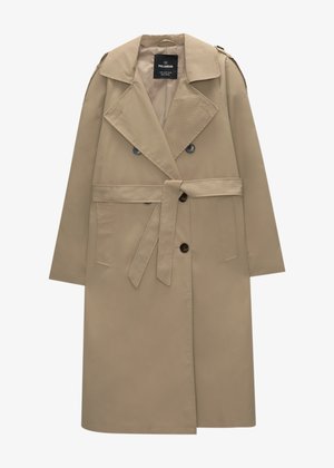 Beige Trenchcoat mit doppelter Knopfleiste, großem Kragen, seitlichen Taschen und einem Bindegürtel. Der Stoff wirkt glatt und wasserabweisend.