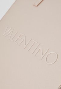 Beige tekstureret læderpung med præget "VALENTINO" logo, glat design og minimalistisk hardwaredetalje.