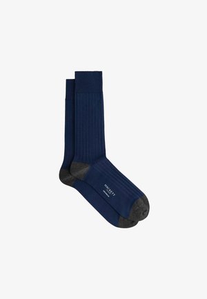 Calcetines acanalados azul marino con talón y puntera gris oscuro. Presentan un logotipo cerca del tobillo. Están fabricados con material suave y extensible.