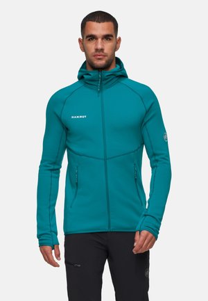 Veste en polaire zippée teal avec un col montant, design ajusté et logo sur la poitrine. Comprend des passages pour les pouces et deux poches latérales zippées.