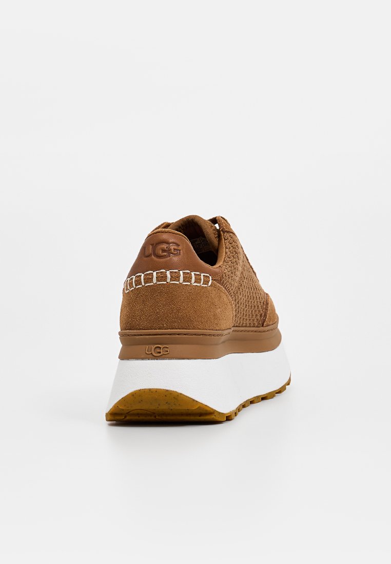 Braune Wildleder- und Mesh-Sneaker mit einer weißen Mittelsohle, der ein strukturiertes Obermaterial und das UGG-Logo an der Ferse aufweist. Runde Zehenform, leichtes Design.