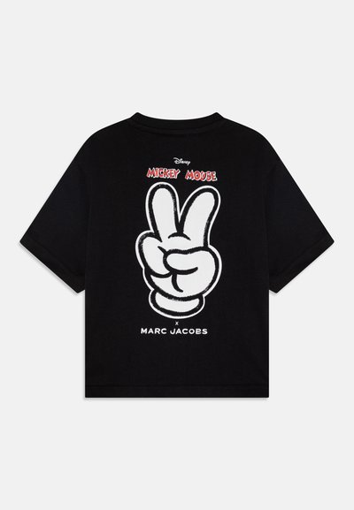 Mustassa puuvillapaidassa on selässä suuri valkoinen Mickey Mouse -rauha-symboli, jonka yläpuolella on punainen teksti "Mickey Mouse" ja brändin nimi alapuolella.