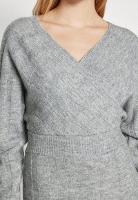 Cardigan grigio a maglia con scollo a V profondo, vita a coste, motivo diagonale testurizzato e maniche lunghe. Tessuto morbido e caldo.