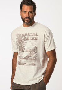 Camiseta de manga corta color crema con un gráfico marrón de palmeras y montañas, con el texto "TROPICAL BLISS" en una fuente audaz.