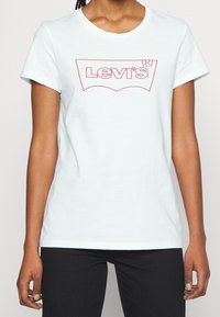 Vit bomull t-shirt med en röd Levi's-logotyp i en böjd design, med en klassisk rund halsringning och korta ärmar.