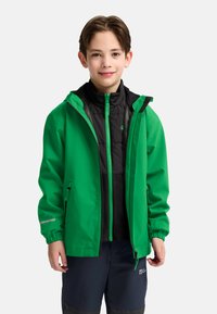 Groene waterdichte jas met een capuchon, ritssluiting aan de voorkant en elastische manchetten over een zwart geïsoleerd vest. Ritsaccenten in felgroen.