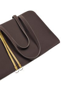 Brązowa torba wykonana z tkaniny, z dwiema długimi, cienkimi uchwytami. Posiada złote paski akcentujące przymocowane do metalowych pierścieni. Gładka tekstura i prosty design.