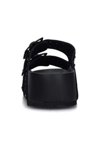 Sandales noires avec trois sangles ajustables, une tige texturée et une semelle épaisse et mate. Présente un design minimaliste et une silhouette plate.