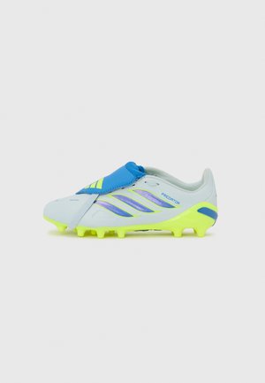 Bota de fútbol azul claro con detalles amarillos, superficie texturizada, correa azul y rayas moradas distintivas. Múltiples tacos en la suela.