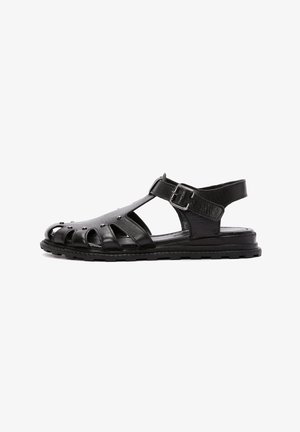 Sandalias de cuero negro con diseño de punta abierta, lados recortados y hebilla lateral. La suela es texturizada para ofrecer agarre y comodidad.