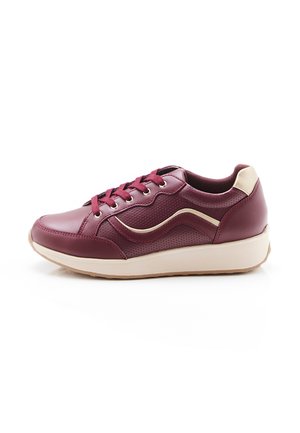 Sneaker van kastanjebruin leer met beige zool en hielenaccent, vetersluiting en een subtiel golvend patroon aan de zijkant.