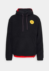 Schwarzer Fleece-Hoodie mit rotem Innenfutter, Fronttasche, verstellbarem Kapuzenzug und einem gelben runden Logo mit einer Silhouette. Mit bunten Kordeln akzentuiert.