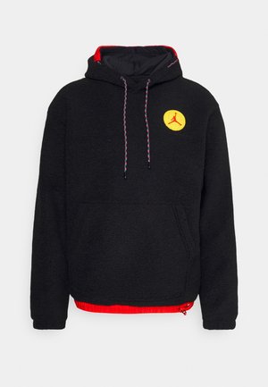 Schwarzer Fleece-Hoodie mit rotem Innenfutter, Fronttasche, verstellbarem Kapuzenzug und einem gelben runden Logo mit einer Silhouette. Mit bunten Kordeln akzentuiert.
