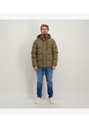 Olijfgroene pufferjack met capuchon, gequilt ontwerp, voorzak met rits, gecombineerd met blauwe spijkerbroek en witte sneakers.