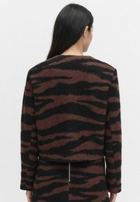 Brown and black striped cropped sweater with a soft texture and long sleeves. Features a simple neckline and straight cut.