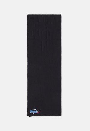 Bufanda de punto en negro sólido, con textura acanalada. Pequeño logotipo bordado en azul, rojo y blanco en la esquina inferior izquierda.