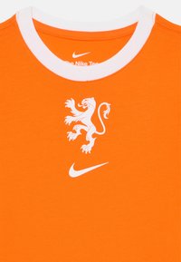 Orange bomull T-shirt med en vit rund krage, med en vit lejon grafik och en vit Nike-logga framtill.