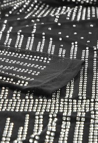 Black fabric with a textured surface, featuring silver sequins arranged in vertical and horizontal patterns.