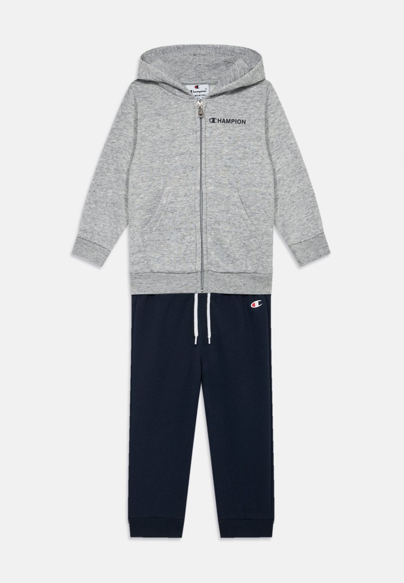 Szara bluza z kapturem na zamek, z przednimi kieszeniami, zestawiona z granatowymi spodniami dresowymi z sznurkiem i akcentem logo. Materiał mieszanka bawełny.