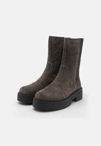 Suede ankle boots in dark gray, featuring a rounded toe, thick black sole, and elastic side panels for easy wear. Textured finish.