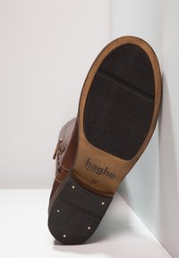 Botte en cuir marron avec une finition texturée, dotée d'une semelle en bois, de clous dorés en accent et d'un logo en dessous. Taille 37.