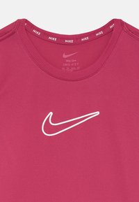 T-shirt Nike Dri-FIT de couleur rose vif, avec un col rond, des manches courtes et un logo swoosh Nike blanc à l'avant.
