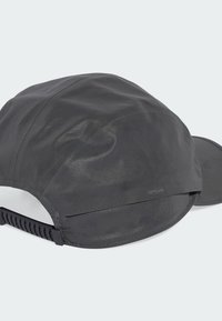 Black cap made of water-resistant fabric, featuring a curved brim, adjustable strap, and smooth texture with a subtle sheen.