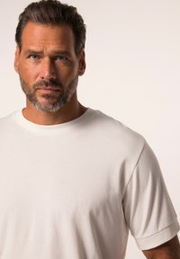 T-shirt bianca in cotone con collo rotondo e maniche corte. Il tessuto sembra morbido con una finitura liscia. Design minimal, senza motivi o dettagli.