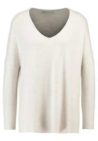 Skórzany sweter w kolorze kremowym, z głębokim dekoltem w kształcie V, opadającymi ramionami i luźnym fasonem. Teksturowana tkanina z delikatnym wzorem. Długie rękawy.