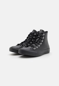 Schwarze High-Top-Sneaker aus glattem Leder, mit metallischen Ösen, flachen schwarzen Schnürsenkeln und strukturierten Gummisohlen mit einem Profilmuster.
