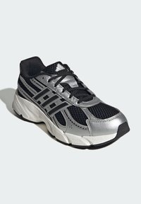 Čierne a strieborné športové tenisky s vrchnou časťou z sieťoviny, reflexnými akcentmi a polstrovanou podrážkou. Má čierne šnúrky a polstrovaný golier.