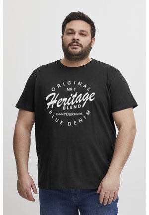 Schwarzes Baumwoll-T-Shirt mit fettem weißen Text: "Original Heritage Blend" mit Akzenten und kreisförmigem Design. Kurze Ärmel und Rundhalsausschnitt.