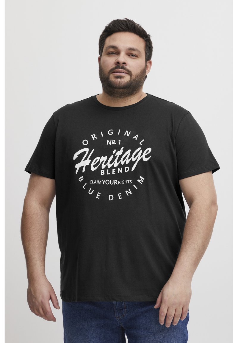Juodas medvilnės marškinėliai su drąsiais baltais užrašais: "Original Heritage Blend" su akcentais ir apvaliu dizainu. Trumpomis rankovėmis ir apvalia iškirpte.