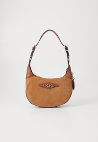 Bolso bandolera de ante color canela con detalles en cuero marrón, herrajes dorados y placa con el logo. Forma curva con una correa ajustable única.