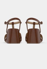 Sandales à talons brunes avec une plateforme épaisse, dotées d'une bride arrière avec boucle réglable, une texture lisse et un design ouvert sur le côté.